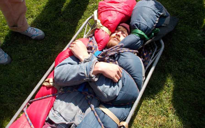 a person lies in a stretcher during a wilderness first aid training